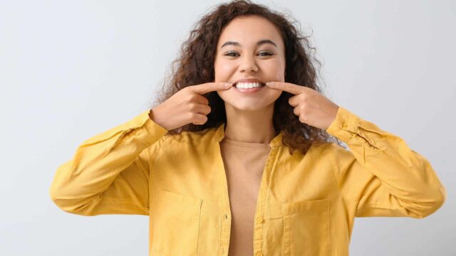 a girl wearing yellow shirt showing her teeths