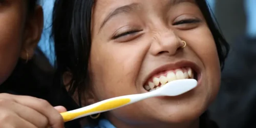 Person brushing teeth in the morning to maintain daily oral hygiene