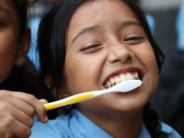 Person brushing teeth in the morning to maintain daily oral hygiene