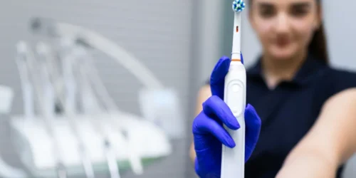 Dental professional wearing gloves holding an electric toothbrush in a clinic